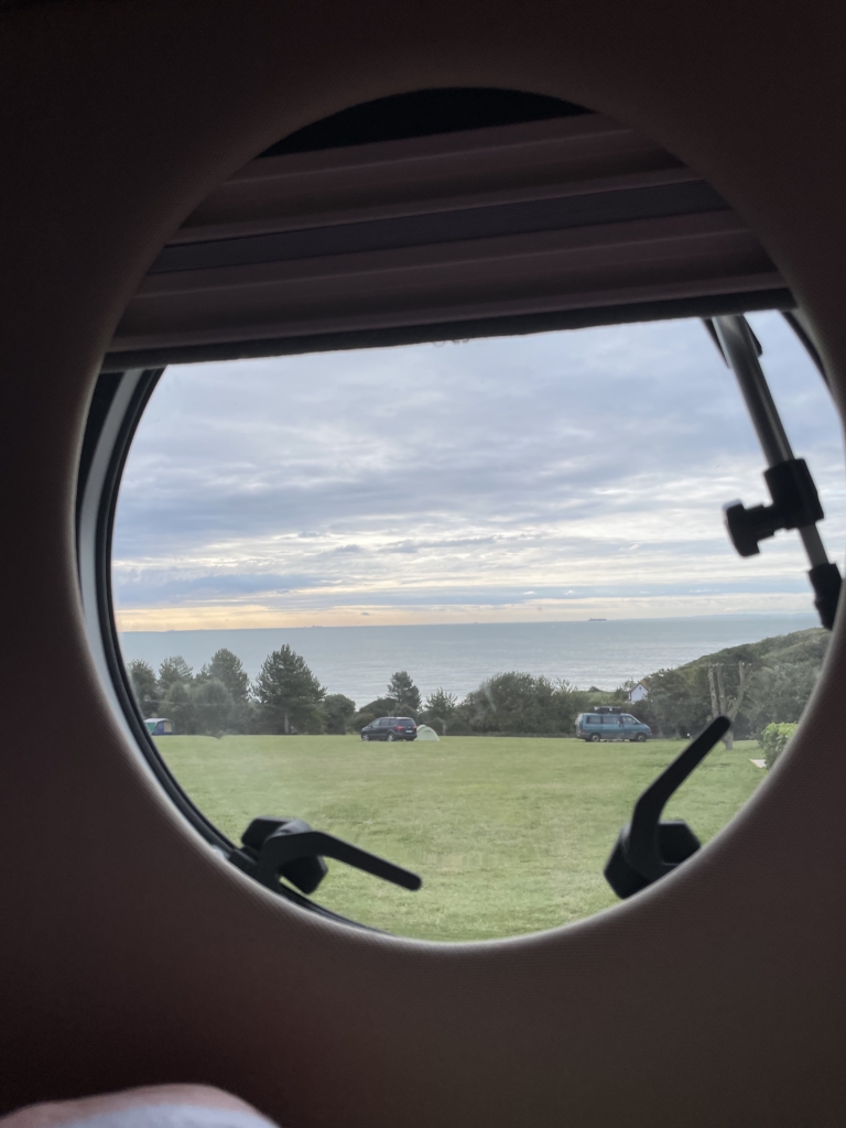 Blick aus einem runden Wohnmobilfenster auf das Meer